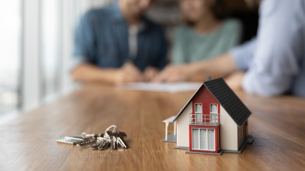 Close up of a set of keys and a model house on a table