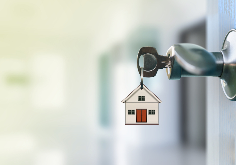 Open Door With Keys In Keyhole. The keychain is a model house.