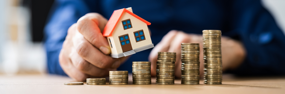 A model house is moved up increasingly high piles of coins - representing property growth