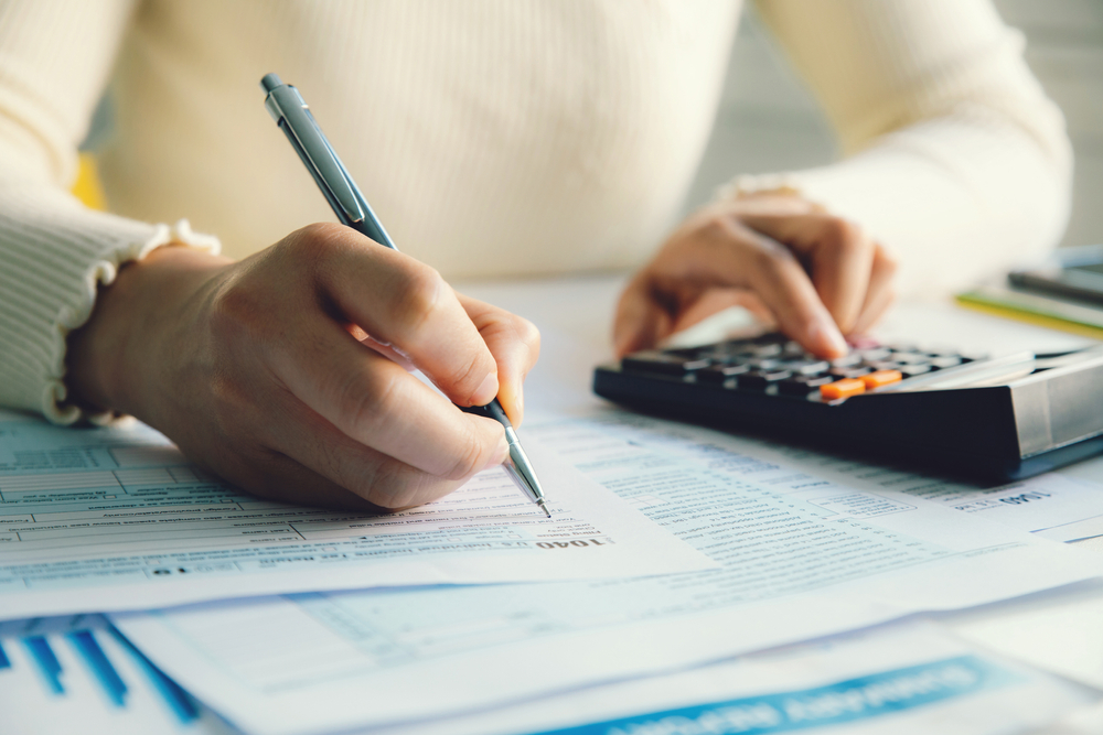 Woman Calculating Personal Income Tax with Forms, a Pen, and a Calculator