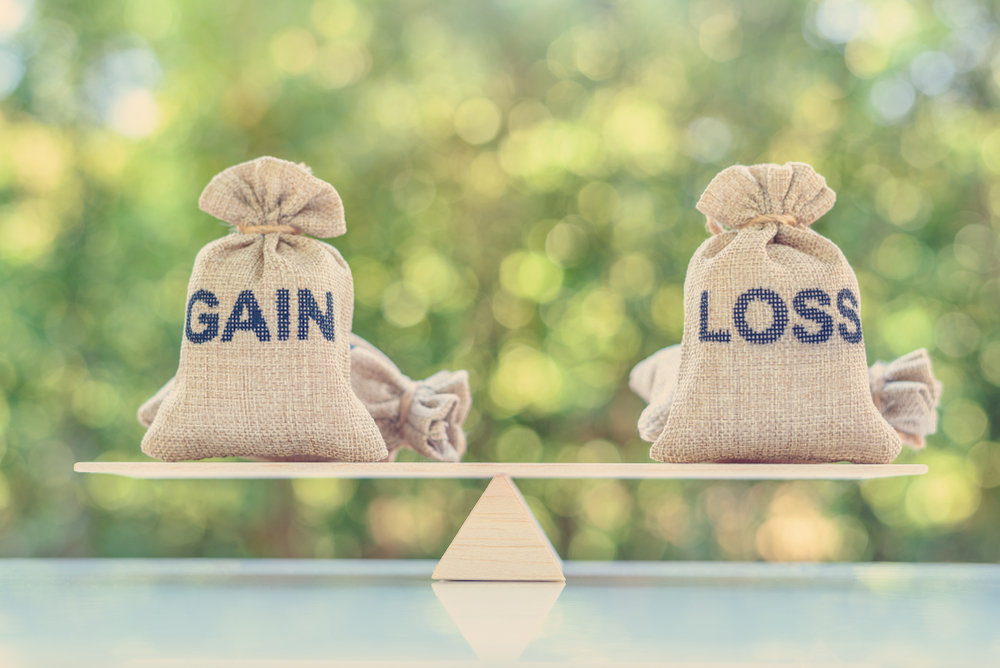 Two burlap sacks labelled "Gain" and "Loss" on either side of a balanced wooden scale