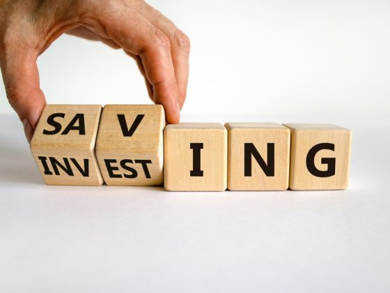 A hand changing cubes between the words saving and investing