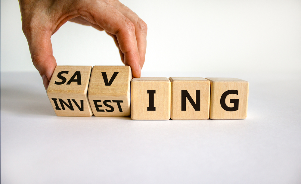 A hand changing cubes between the words saving and investing